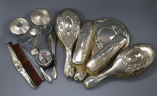 A George V repousse silver six piece dressing set, three silver topped toilet bottles, etc.